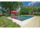Beautiful backyard pool with red umbrellas, lush landscaping, and a charming waterfront view for ultimate relaxation at 2491 Island Dr, Longwood, FL 32779
