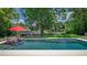 Backyard pool with two chairs, red umbrella, and peaceful waterfront view, surrounded by lush greenery and privacy at 2491 Island Dr, Longwood, FL 32779