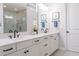 Elegant bathroom featuring double sinks, white cabinetry, sleek fixtures, and a well-lit vanity mirror at 2841 Willowseed Ln, St Cloud, FL 34772