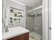 Contemporary bathroom features a glass shower with grey tiling, a white sink, and decorative display shelves at 2918 Wessex St, Orlando, FL 32803