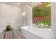 Modern bathroom with a freestanding tub and large window overlooking lush landscaping at 2918 Wessex St, Orlando, FL 32803
