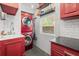 Well-lit laundry room features a stacked red washer and dryer, white subway tile, and stylish cabinetry at 2918 Wessex St, Orlando, FL 32803