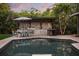 Outdoor kitchen and dining area with a built-in grill, bar, and table adjacent to the pool at 2918 Wessex St, Orlando, FL 32803