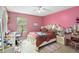A comfortable bedroom with pink walls, a ceiling fan, a study desk, and decoratively framed bed and vanity at 294 Hunt St, Clermont, FL 34711