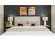 A relaxing bedroom with a white bed frame, stylish lamps, neutral colored pillows, and modern art above the headboard at 393 Meadowland Pt, Oviedo, FL 32765