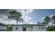 Bright back exterior showcasing the windows of the house with a yard and blue skies at 6054 Sw 154Th Place Rd, Ocala, FL 34473