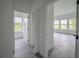 Hallway showcasing the gray wood flooring and white walls that leads to a bright room at 6054 Sw 154Th Place Rd, Ocala, FL 34473