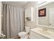 Neutral bathroom features a shower-tub combination with a gray striped curtain, toilet, vanity, and decorative cabinet at 620 Fruitwood Ave, Winter Springs, FL 32708