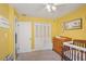 A cozy Bedroom features a closet and a wooden crib, paired with yellow walls and neutral carpet at 620 Fruitwood Ave, Winter Springs, FL 32708