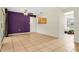 View of a spacious living room with tile flooring, purple accent wall, ceiling fan, and access to the kitchen at 715 Wedge Ln, Poinciana, FL 34759