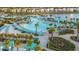 Wide aerial shot of a community pool with a sandy beach, lounge chairs, umbrellas, and palm trees at 8045 Lost Shaker Ln, Kissimmee, FL 34747