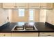 Galley kitchen features a stainless steel double sink, black counter, and white cabinets at 860 N Orange Ave # 371, Orlando, FL 32801