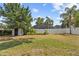 Fenced backyard with mature trees, fresh green grass, and a storage shed at 913 Moss Ln, Winter Park, FL 32789