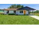 Charming single-story home with well-maintained lawn, freshly painted in white with yellow door and convenient carport at 1105 Valencia Ave, Haines City, FL 33844