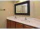 Bathroom vanity featuring double sinks, granite countertop, and a decorative framed mirror at 11994 Mckinnon Rd, Windermere, FL 34786