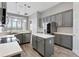 Open kitchen with gray cabinets, stainless steel appliances, a center island, and a breakfast bar at 12411 Scarlett Sage Ct, Winter Garden, FL 34787