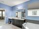 Modern bathroom with double vanity, large mirror, soaking tub, and stylish tile accents at 14962 Fells Ln, Orlando, FL 32827