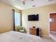 A bedroom features a ceiling fan, side table with chair, TV, dresser, and a comfortable bed with decorative pillows at 14962 Fells Ln, Orlando, FL 32827
