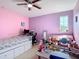 Bright bedroom with pink and purple walls, a daybed, a desk, and ample natural light at 14962 Fells Ln, Orlando, FL 32827