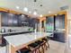 This kitchen boasts dark cabinetry, granite counters, stainless appliances, and a large island with barstool seating at 14962 Fells Ln, Orlando, FL 32827
