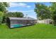 Expansive backyard featuring a screened-in pool area and well-kept lawn, perfect for outdoor enjoyment at 157 Ambergate Ct, Debary, FL 32713