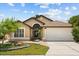 Charming single-story home featuring a two-car garage, well-manicured lawn, and beautifully landscaped front yard at 219 Old Mill Cir, Kissimmee, FL 34746