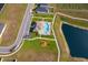 Aerial view of the community pool and park next to a pond with houses and cultivated fields nearby at 2226 Majestic Span Ave, Eagle Lake, FL 33839
