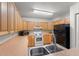 Functional kitchen featuring ample wood cabinets, essential appliances, and a double stainless sink at 225 Indiana St, Leesburg, FL 34748