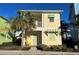 Charming yellow two-story home with lush landscaping and a welcoming front porch, and a palm tree at 3013 Latitude Ln, Kissimmee, FL 34747