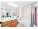 Bright bathroom featuring a tub-shower combo, cherry vanity, and large mirror with decorative lighting at 3697 Rolling Hills Ln, Apopka, FL 32712