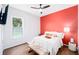 Cozy bedroom featuring an accent wall, hardwood floors, and a well-lit window at 3697 Rolling Hills Ln, Apopka, FL 32712