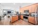 Modern kitchen with stainless steel appliances, wood cabinets, and a breakfast bar overlooking the living area at 3697 Rolling Hills Ln, Apopka, FL 32712