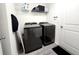 Functional laundry room featuring black appliances, storage shelves, and laminate flooring at 3838 Whitetail Ct, St Cloud, FL 34772