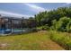 Spacious backyard with lush greenery surrounding a screened-in pool enclosure at 4640 Eagle Peak Dr, Kissimmee, FL 34746