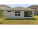 View of the back exterior with a screened in porch and a glimpse of the green backyard at 5079 Royal Point Ave, Kissimmee, FL 34746