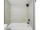 Close-up of a shower with white tub, black shower head, and marbled-look tiling at 5168 Conroy Rd # 35, Orlando, FL 32811