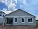 Rear exterior featuring gray siding, white window trim, covered patio, and sliding glass doors for natural light at 5250 Teirgarten St, St Cloud, FL 34771