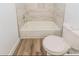 Bathroom with bathtub, tile surround, wood-look flooring, and white toilet at 5311 Ansonia Ct, Orlando, FL 32839