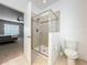 Bathroom featuring tiled shower with glass door, adjacent to a toilet and open doorway to the bedroom at 5772 Laurel Cherry Ave, Winter Garden, FL 34787