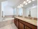 Well-lit bathroom with double sinks, granite countertops, and a soaking tub for relaxation at 5772 Laurel Cherry Ave, Winter Garden, FL 34787