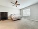 Neutral bedroom with a ceiling fan, large window, and a dark wood dresser for ample storage space at 5772 Laurel Cherry Ave, Winter Garden, FL 34787