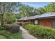 Charming brick house with a well-manicured yard, mature trees, and solar panels on the roof at 628 Riverpark Cir, Longwood, FL 32779