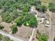 Aerial shot of a property with a circular driveway, lush trees, and a pristine pool in a rural setting at 6686 Se 135Th St, Summerfield, FL 34491
