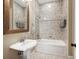 Tiled bathroom with a pedestal sink, a built-in tub and tiled shower, creating a classic aesthetic at 6686 Se 135Th St, Summerfield, FL 34491