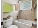 Well-lit bathroom with a tub, window, and neutral-toned tile at 6686 Se 135Th St, Summerfield, FL 34491
