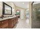 Spacious bathroom features a dark wood vanity, decorative window and large shower with glass door at 6686 Se 135Th St, Summerfield, FL 34491