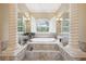 Luxurious bathroom with tub beneath a window flanked by mirrored pillars, offering a spa-like experience at 6686 Se 135Th St, Summerfield, FL 34491