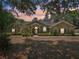 Inviting single-story home featuring manicured landscaping, mature trees, and a stately facade at sunset at 6686 Se 135Th St, Summerfield, FL 34491