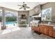 Outdoor kitchen and fireplace with a view of the screened-in pool area at 6686 Se 135Th St, Summerfield, FL 34491