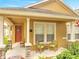 Charming covered porch with comfortable seating, stone-accented columns, and manicured landscaping at 6837 Pasturelands Pl, Winter Garden, FL 34787